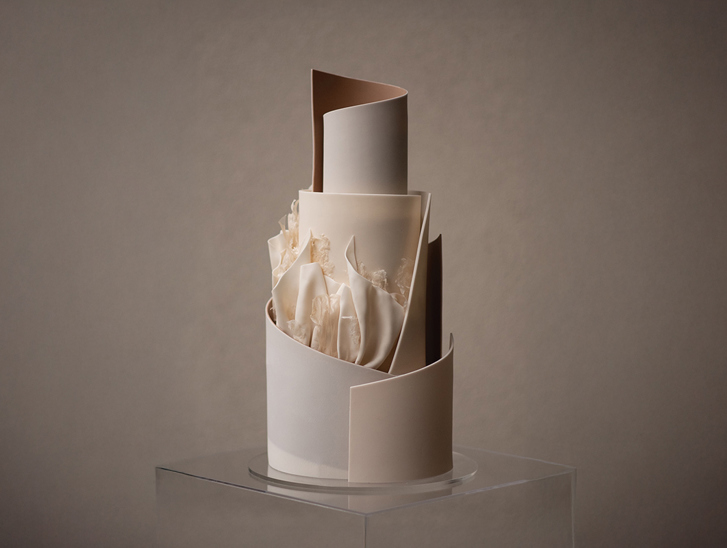 A neutral coloured, tiered cake with signature YiShi Cake ruffles